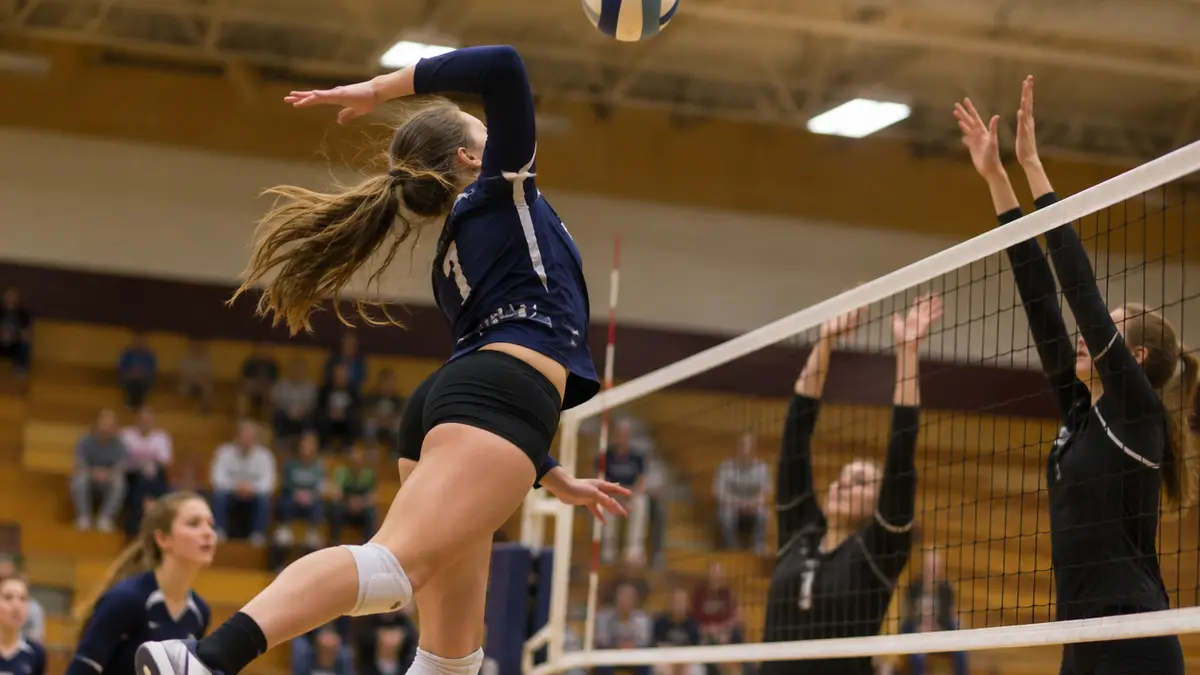 High school volleyball player jumping to spike the ball in a gym
